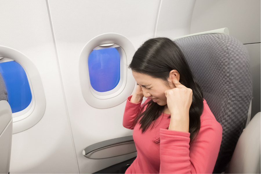 woman holding ear on plane